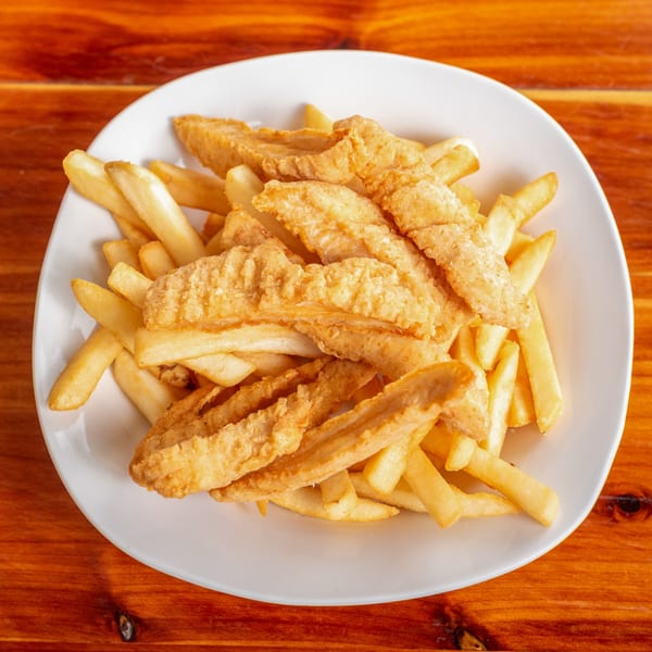 Crispy fried fish strips and golden french fries piled high on a white plate.